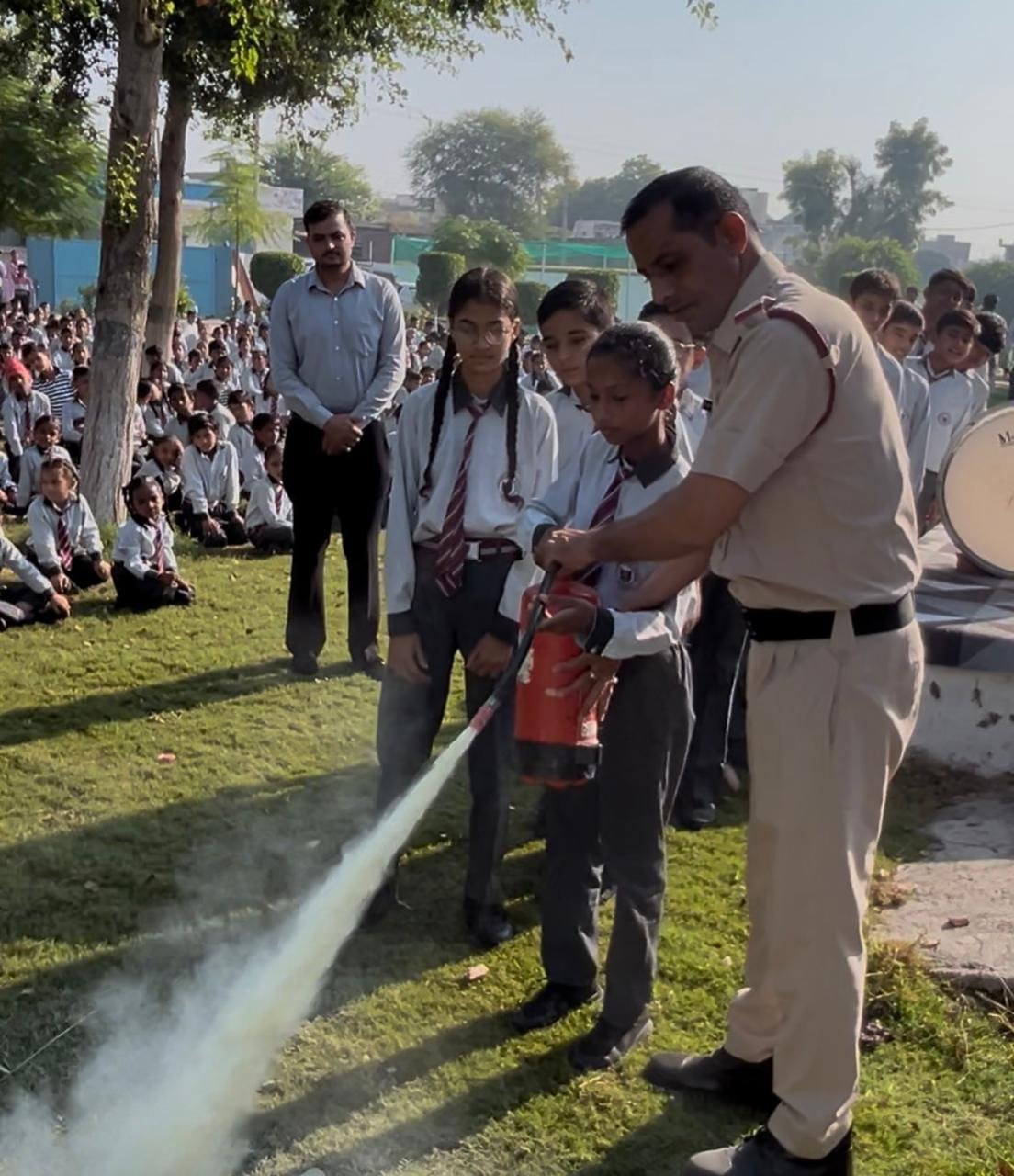 Fire safety mock drill conducted by the Fire Department at Samsara Public School, Shekhukheda; students shown fire-extinguishing techniques.